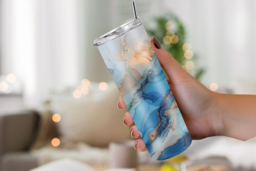 Preview: Thermobecher mit abstraktem Ozean-Design – Frische Eleganz (590ml) Preview: Thermobecher mit einem abstrakten Ozean-Design in Blau-, Türkis- und Goldtönen, gehalten in einer Hand vor einem gemütlich beleuchteten Innenraum mit unscharfen, warmen Lichtakzenten im Hintergrund.